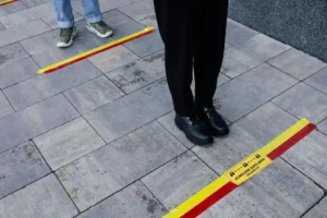 Two people stand in line behind floor marking tape