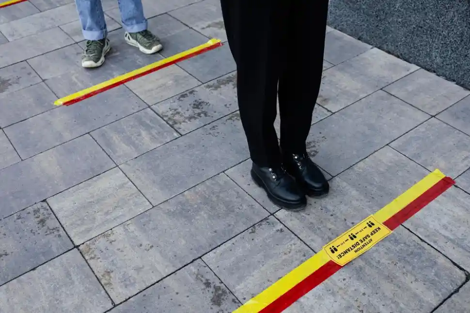 Two people stand in line behind floor marking tape