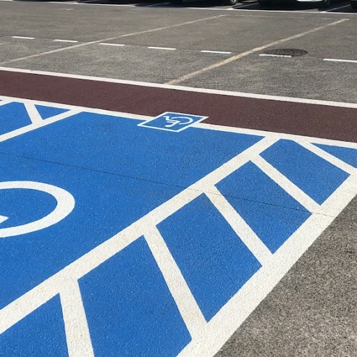 High-visibility accessible parking stencil markings in a parking lot with blue paint and white striping.