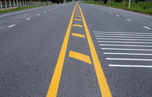 Yellow and white road markings on asphalt.