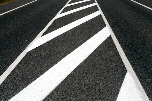 White diagonal road markings on asphalt.